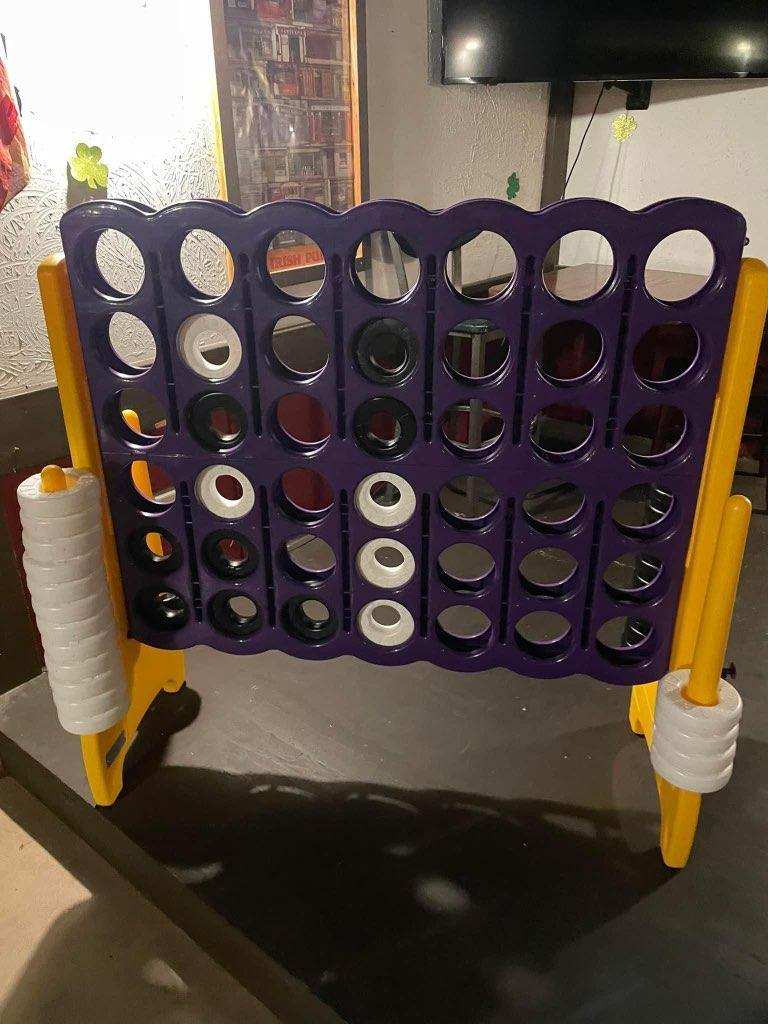 Giant four-in-a-row game with a purple grid and yellow stand at O’Mally’s
