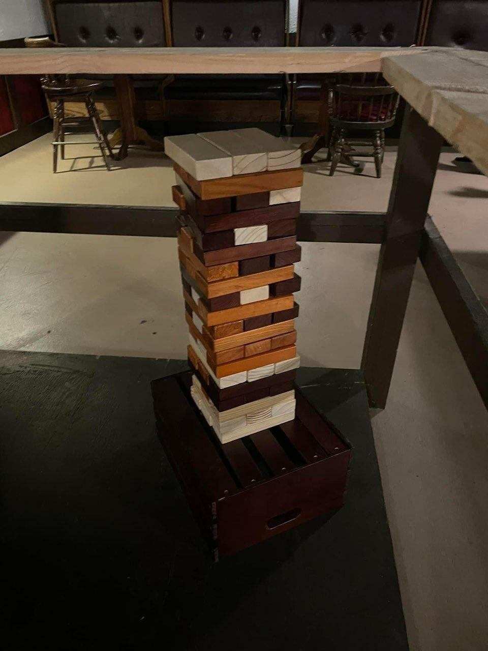 Giant wooden block-stacking tower game on a wooden crate next to a table at O’Mally’s