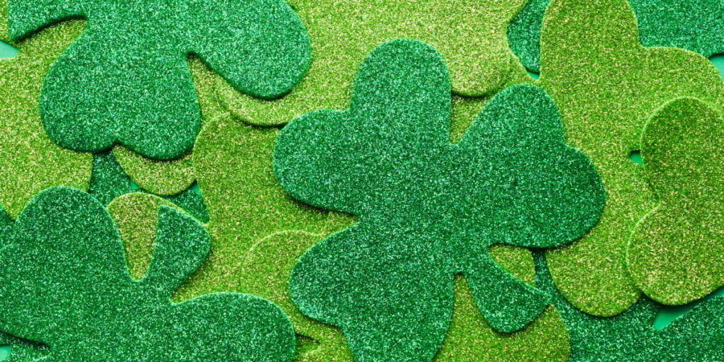 Glittery green shamrocks scattered densely, evoking a festive St. Patrick’s Day mood. The bright hues and sparkles convey a joyful, celebratory tone.