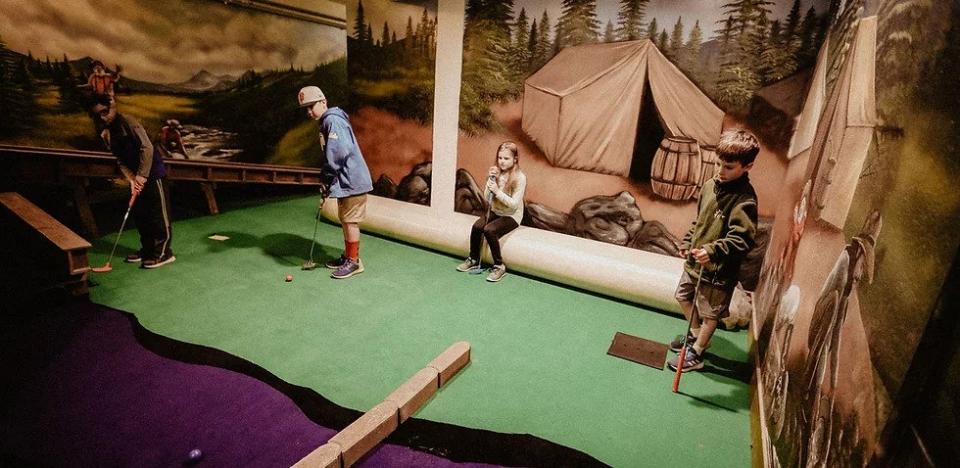 4 kids playing miniature golf at Old Sacramento's Underground Mini Golf course.
