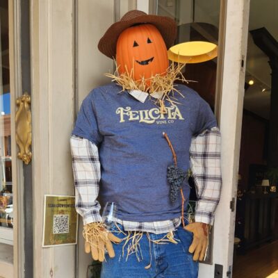Felicità Wine Co. scarecrow with a jack-o'-lantern head, cowboy hat and Felicità T-shirt